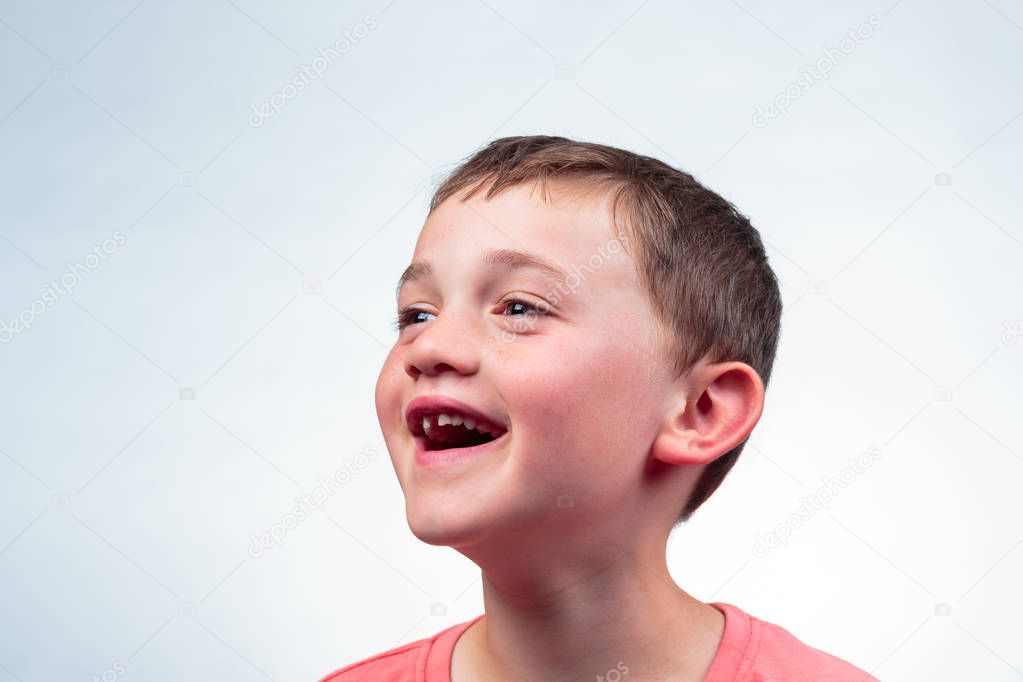Close up portrait of a caucasian 8 year old boy smiling, milk tooth missing. isolated on light background