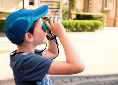 8 yaşında bir çocuk oyuncak dürbün seyir mavi beyzbol şapkalı
