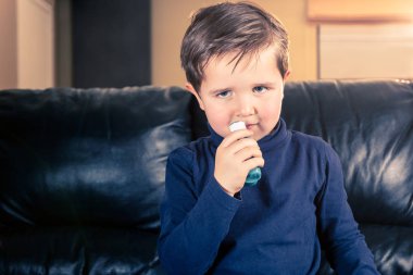 Şirin 5 yaşındaki yürümeye başlayan çocuk siyah deri kanepe oturma onun astım inhaler holding