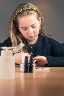 Genç kız evde manikür için hazır mutfak masasında kozmetik araçlar kümesi ile
