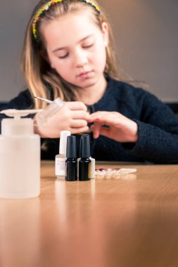 Manikür için kozmetik araçlar genç kız tırnak törpüsü kullanırken mutfak masasının üzerinde ayarlayın. sığ derinlik-in tarla, tırnak cilası şişe odaklanmak