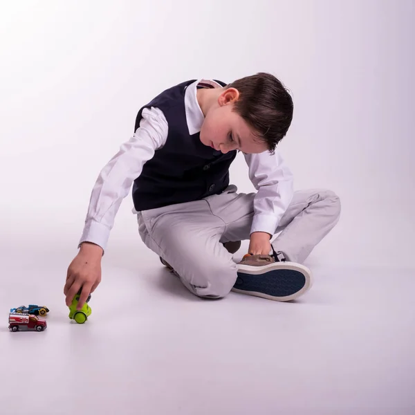 Young boy in suit sitting down playing — Stock Photo, Image