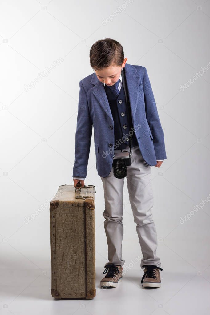 Young boy dressed up with photo camera and suitcase