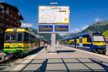 Grindelwald, İsviçre - 30 Temmuz 2019: Wengernalpbahn ve Berner Oberland Bahn trenleri güneşli bir günde tren istasyonunda