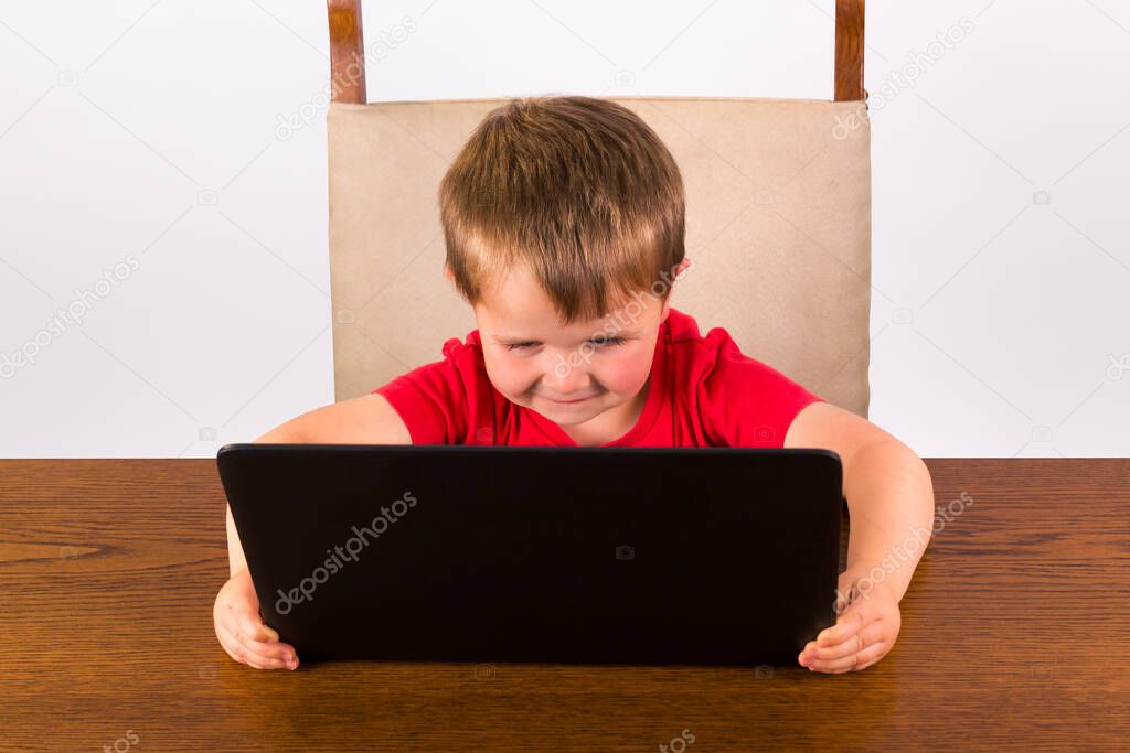 4 year old toddler having fun with a laptop computer. high angle view isolated on white background