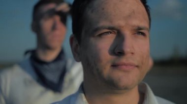 İki adam gün batımında mesafeye bakıyor. Kamera sallama efektiyle