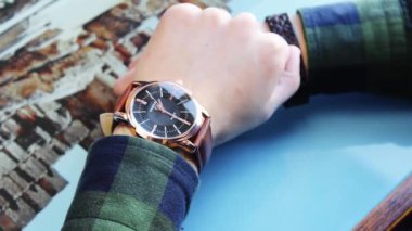 Masadaki adam altın kol saatine bakıyor.