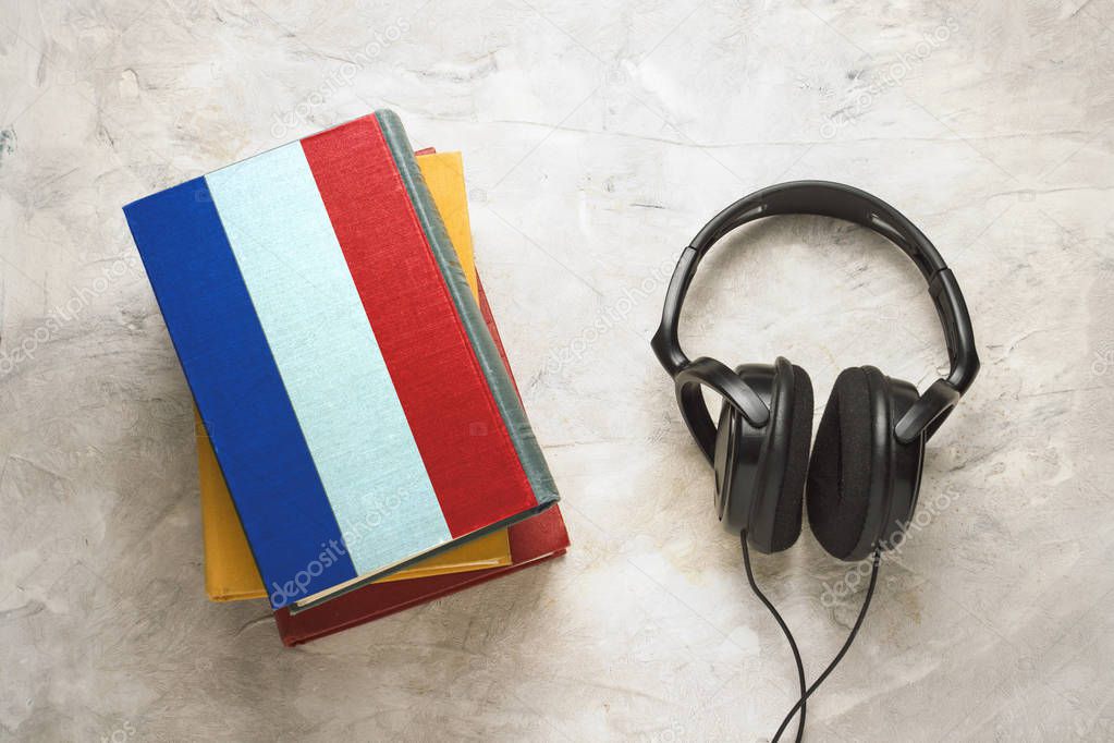 Headphones and a pile of books. The upper book has a cover in the form of a flag of France. Concept audiobooks. Learning languages. French language.