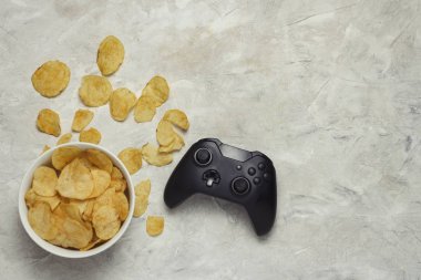 Gamepad ve cips hafif bir taş zemin üzerine bir kase. Bilgisayar oyunları ve spor turnuvaları kavramı. Düz yatıyordu, en iyi görünümü.