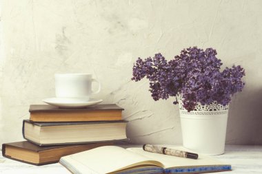 Leylak Beyaz bir dekoratif demet, kitaplar, açık günlük, beyaz fincan kahve beyaz taş zemin üzerine yığını.