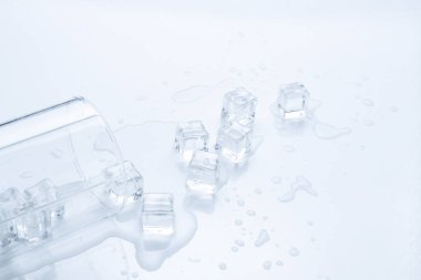 Dökülen bardak su ile hafif bir arka plan üzerinde buz.