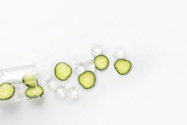 Su, salatalık dilimleri ve buz üzerinde hafif bir arka plan yenileme ile dökülen cam.