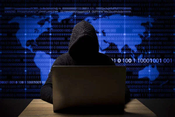 hacker in a jacket with a hood with a laptop sits at the table. Added identity theft icons, account hijacking, bank data theft and world map.