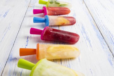 Ev yapımı renkli bir ışık ahşap arka plan üzerinde buzlu şeker meyve. Çilek, limon, nane limon, portakal, vişne, karışık.