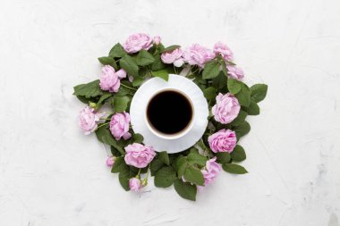 Hafif bir taş zemin üzerine siyah kahve ve pembe güller ile beyaz fincan. Düz yatıyordu, en iyi görünümü.