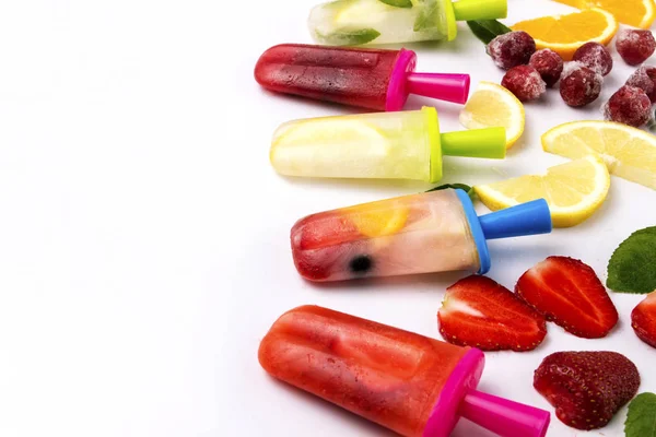 Multicolored bright fruit popsicle with strawberry, cherry, lemon, orange, lemon and mint and slices fresh fruit on a light white background.