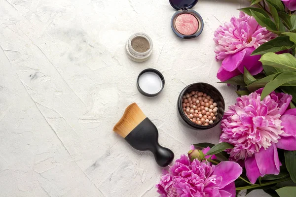 Decorative cosmetics. Pink peonies on a light background. Top view