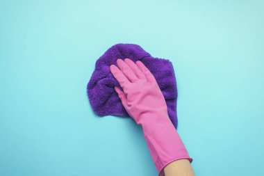 Pembe eldivenleri, kir ve toz mavi bir arka plan üzerine çıkarmak için peçeteye holding ile el. temizlik hizmet anlayışı. Düz yatıyordu, en iyi görünümü.