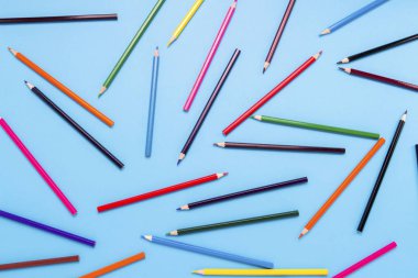 Renkli kalemler mavi bir arka plan karede boyunca dağınık. Düz yatıyordu, en iyi görünümü.