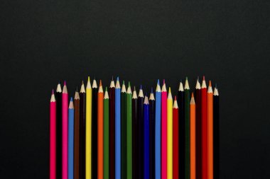 Renkli kalemler siyah bir zemin üzerine bir dalga şeklinde ortaya koydu. Düz yatıyordu, en iyi görünümü.