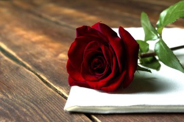 Kırmızı gül ahşap bir masa üzerine beyaz bir kumaş üzerinde. Romantik kavramı. Düz yatıyordu, en iyi görünümü 