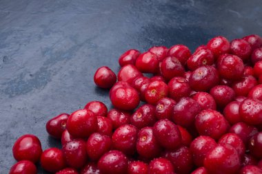Taze kiraz su ve çiğ damlaları ile koyu mavi bir taş arka plan üzerinde aldı. Hasat kavramı. Düz yatıyordu, en iyi görünümü.