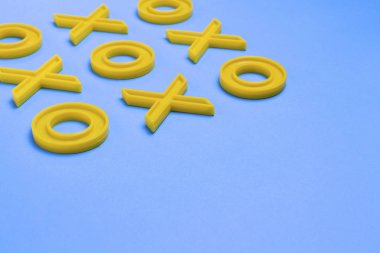 Sarı plastik haçlar ve mavi bir arka plan üzerinde üç taş oynamak için zeroches. Kavram Xo kazanmak Challenge. Çocuklar için eğitici bir oyun.