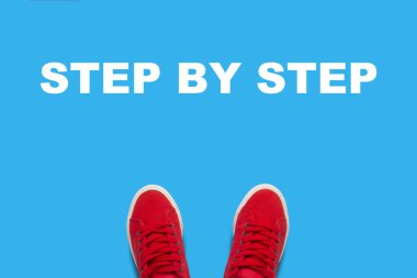 Adım adım metin ile mavi bir arka plan üzerinde duran kırmızı spor ayakkabılar bacaklar. Eylem dizisini kavramı. Düz yatıyordu, en iyi görünümü.