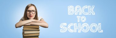 Beyaz elbise ve Gözlük Genç kız mavi bir arka plan üzerinde kitapların bir yığınına ellerini koymak. Eklenen metin okul için. Genç bir öğrenci, bir öğrenci ve öğretim yılı başında kavramı.