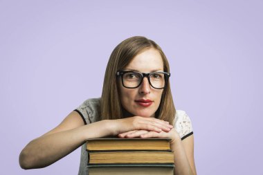 Bir genç kız beyaz bir elbise ve gözlük bir yığın kitap gri bir arka plan üzerinde ellerini koymak. Genç öğrenci ve eğitim kavramı.
