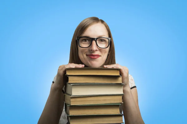白いドレスと眼鏡の少女が青い背景に本の山に手を置いた 若い学生と教育の概念 — ストック写真