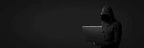 戴着帽衫的人在黑暗背景下手持手提电脑 黑客的概念 窃取用户数据 信用卡 电子邮件 个人文件 — 图库照片
