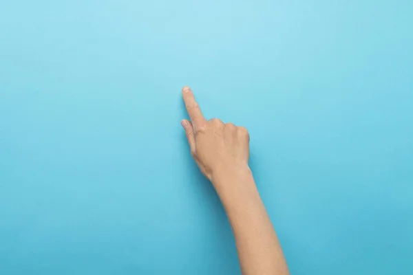 Female hand touches finger a blue background. Flat lay, top view.