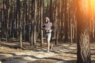 Bir çam ormanı içinde çalışan bir kapüşonlu adam. Açık eğitim kavramı.
