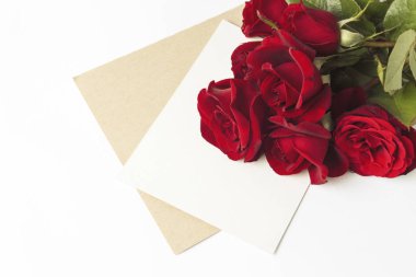 Buket kırmızı gül ve beyaz bir arka plan üzerine bir not olan bir zarf. Kavramı bir romantik hediye. Düğün Temalar.