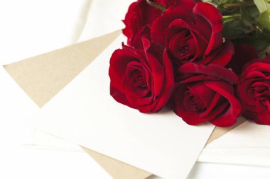 Buket kırmızı gül ve beyaz bir arka plan üzerine bir not olan bir zarf. Kavramı bir romantik hediye. Düğün Temalar.