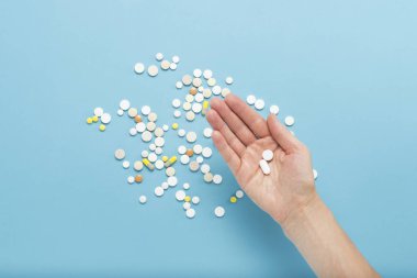 Avuç içinde dağınık hapları ile mavi bir arka plan üzerinde bir hap tutan el. Hastalık, pharmacetiya, ilaç durumunda uyuşturucu alarak kavramı. Doğru ilaç seçimi. Düz yatıyordu, en iyi görünümü.