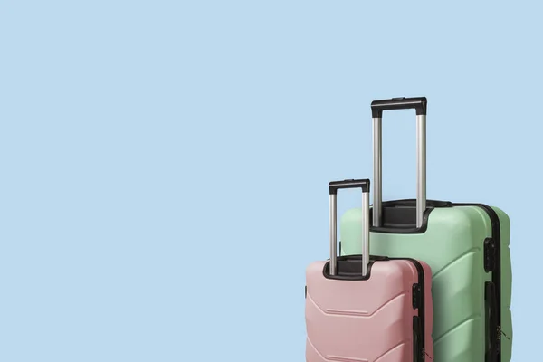 青色の背景に車輪の上 つのスーツケース 休暇旅行 親戚への訪問の概念 ピンクと緑の色 — ストック写真