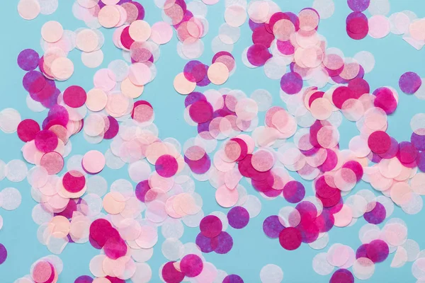 Pink confetti on a blue background. Party and holiday concept. Flat lay, top view.