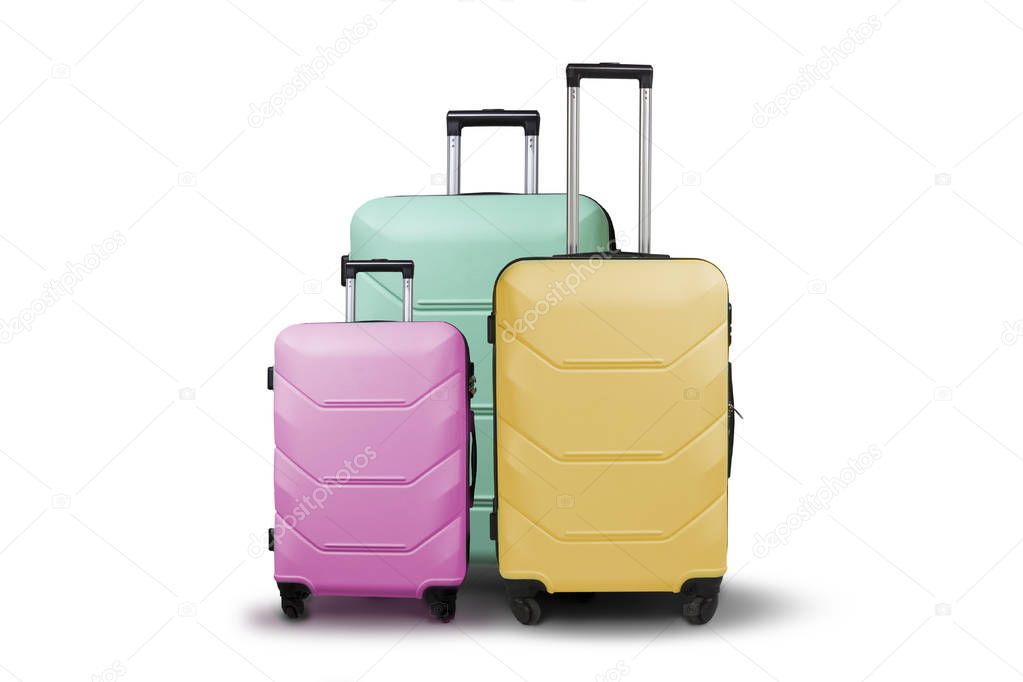 Three multi-colored plastic suitcases on wheels on a white isolated background. Travel concept, vacation trip, visit to relatives.