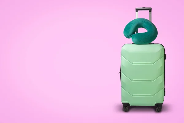 在粉红色背景的塑料手提箱和旅行枕头 旅行的概念 商务旅行 拜访亲友的旅行 — 图库照片