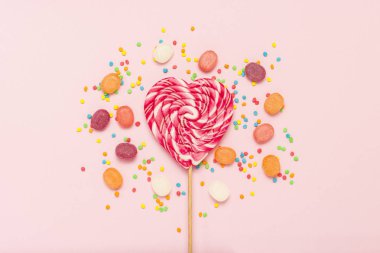 Kalp lolipop ve birden çok tatlılar yavaşça pembe bir arka plan üzerinde renkli. Tatlı ve şekerleme kavramı. Tatlı hediye. Tatlı aşk. Düz yatıyordu, en iyi görünümü.