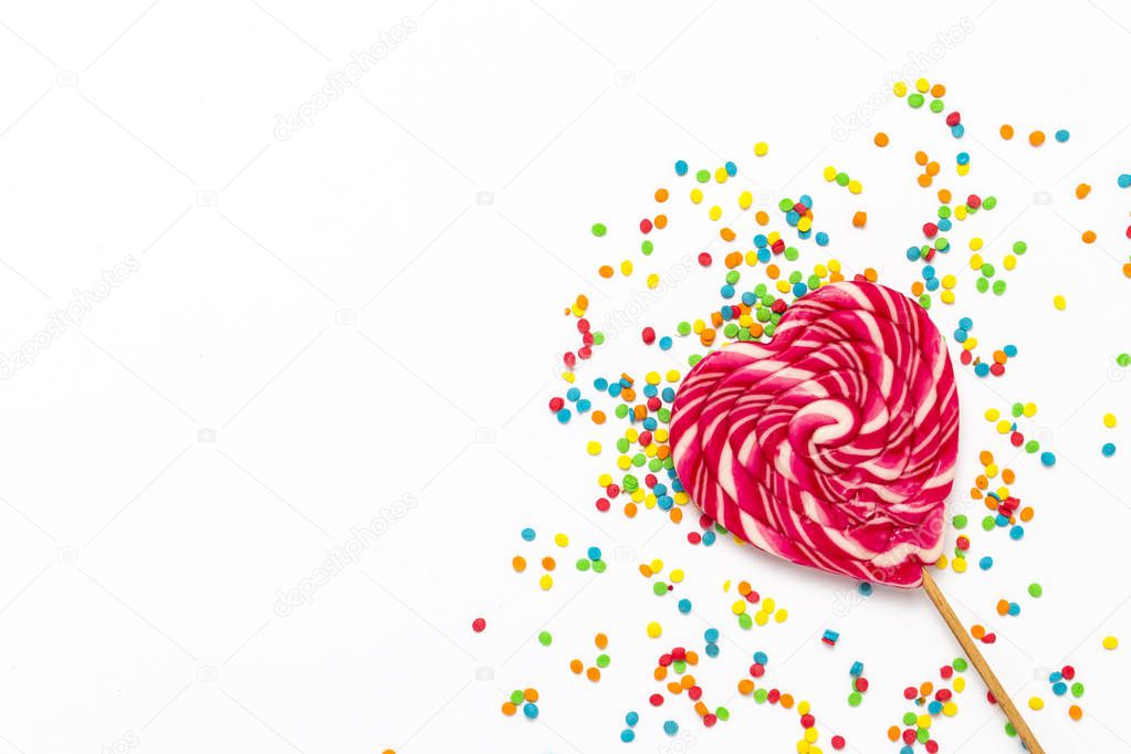 Heart Lollipop and multi coloured sweets on a gently white background. Concept of sweets and candies. Sweet gift. Sweet love. Flat lay, top view.