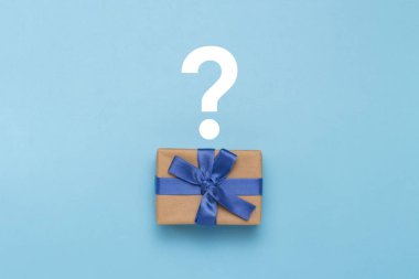 Hediye kutusu ile blue ribbon ve soru işareti mavi bir arka plan üzerinde. Sürpriz, beklenmeyen hediye kavramı. Düz yatıyordu, en iyi görünümü.