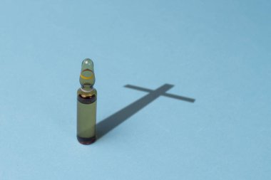 Aşı ampül ve mavi bir arka plan üzerinde haçlar şeklinde bir gölge. Aşı ölüm, uyuşturucu bağımlılığı, tıbbi priporatov, düşük kaliteli uyuşturucu bağımlılığını kavramı.