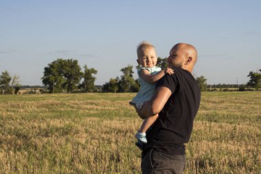 Genç adam bir çocuk onun kollarında alanın arka planı tutar. Çocuklar, mutlu bir aile ile kavram oyunu.