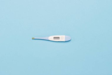 Mavi bir arka plan üzerinde elektronik termometre. Minimalizm. Düz yatıyordu, en iyi görünümü.