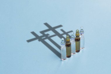 Aşı ampul ve mavi bir arka plan üzerinde haçlar şeklinde bir gölge. Aşı ölüm, uyuşturucu bağımlılığı, tıbbi priporatov, düşük kaliteli uyuşturucu bağımlılığını kavramı.