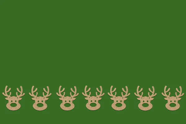 木製のクリスマスおもちゃ頭鹿の緑の背景に底側のパターンが並んでいます 追加テキスト メリー クリスマスと新年あけましておめでとうございます ミニマルなスタイル フラット横たわっていた トップ ビュー — ストック写真