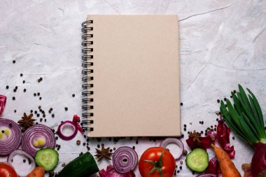 Taze sebze ve not defteri açık renkli üzerinde yemek tarifleri için. Yemek, vejetaryenlik ve sağlıklı beslenme kavramı.